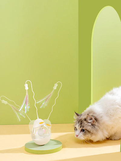 Yellow duck egg shaped tumbler cat toy with a clear middle, containing a yellow ball, and a flexible wand with purple and pink streamers. - Image 5