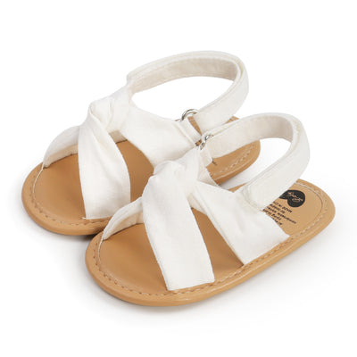 Black baby sandals with knotted cross straps and a matching black floral headband on a white background. - Image 17
