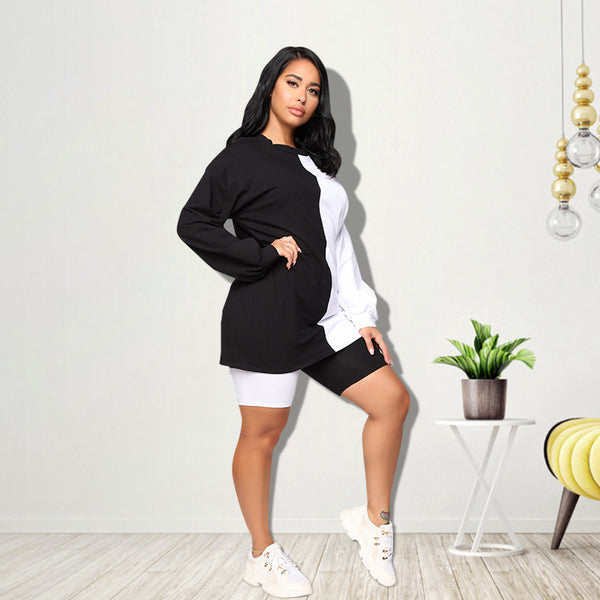 Woman wearing a black and white color-block long-sleeve top and matching shorts with white sneakers.