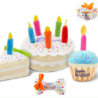 Plush pet toy shaped like a white gift box with colorful polka dots, an orange bow, and "HAPPY BIRTHDAY" ribbon.