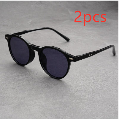 Fashionable round-frame sunglasses with transparent gray frames and dark gray lenses on a gray surface. - Image 7