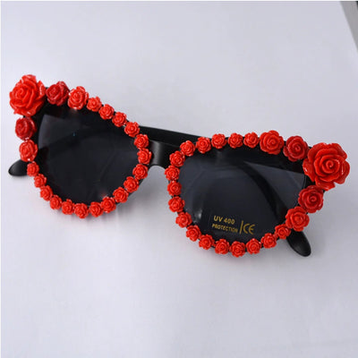 Black cat-eye sunglasses with dark lenses, adorned with small red rose embellishments along the frames. - Image 8