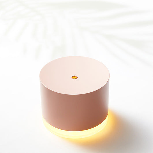 Pink cylindrical mini wireless humidifier with a clear base and a small gold mist outlet on top. - Image 9