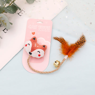 White cat head plush teaser toy with hemp rope, gold bell, and natural spotted feathers on pink packaging. - Image 9