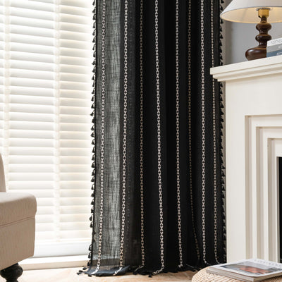Black polyester curtain with white jacquard multi-line pattern and black tassels, draped over a white chair. - Image 3
