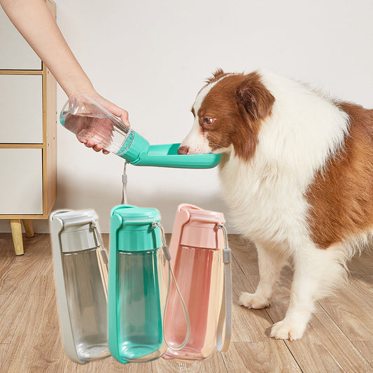 Yellow 450ml portable pet water bottle with a folding drinking trough and white wrist strap, on grass.