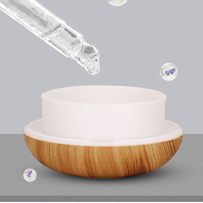 Teardrop-shaped aromatherapy humidifier with light wood grain finish, emitting mist and glowing with purple LED light. - Image 2