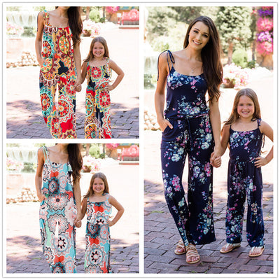 Woman wearing a navy blue floral wide-leg jumpsuit with pink and white flowers, tie-shoulder straps, and a drawstring waist. - Image 11