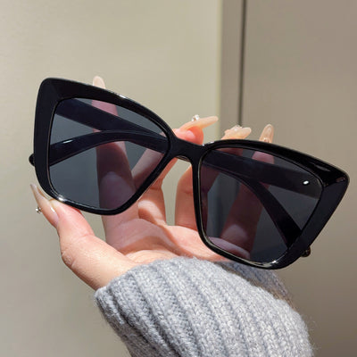 Clear large-frame square glasses held by a hand in a grey knitted sweater, showcasing the transparent plastic frame. - Image 8