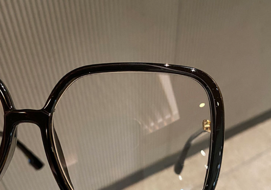 Black oversized square anti-blue light glasses with clear resin lenses and gold metal frame details, held by a hand. - Image 12