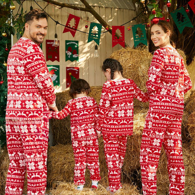 Family of four wearing matching red and white Christmas pajamas with reindeer and snowflake patterns, smiling. - Image 3