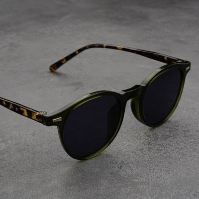 Fashionable round-frame sunglasses with transparent gray frames and dark gray lenses on a gray surface. - Image 13