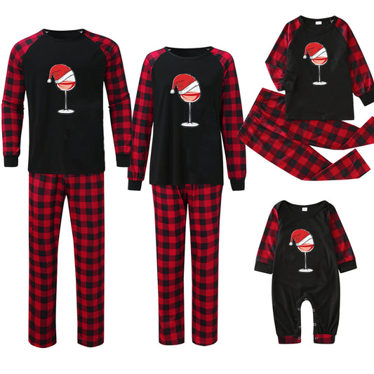 Family matching Christmas pajamas with black tops featuring a wine glass in a Santa hat graphic and red plaid bottoms. - Image 2