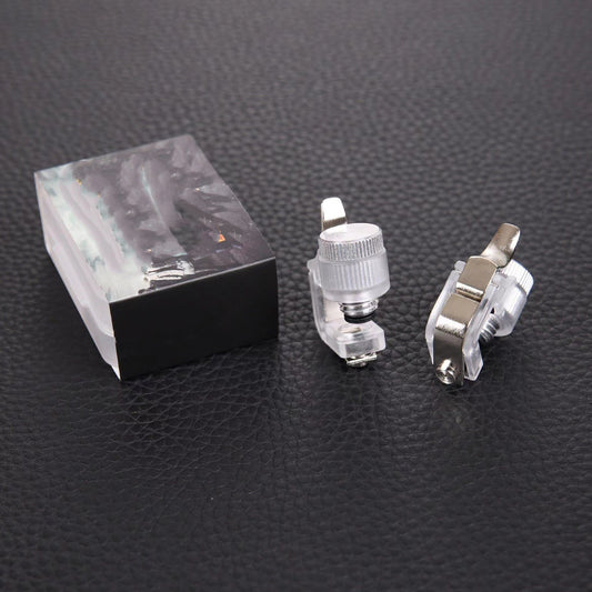 Pair of clear mobile game trigger buttons with silver levers and a clear plastic box on a dark textured surface.