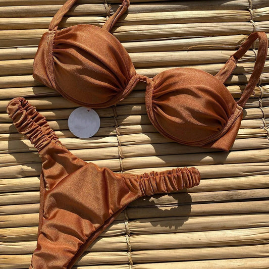 Rust underwire bikini set with ruched top and high-cut bottom, displayed on a woven mat.