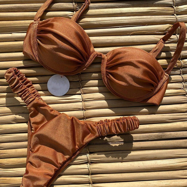 Rust underwire bikini set with ruched top and high-cut bottom, displayed on a woven mat.