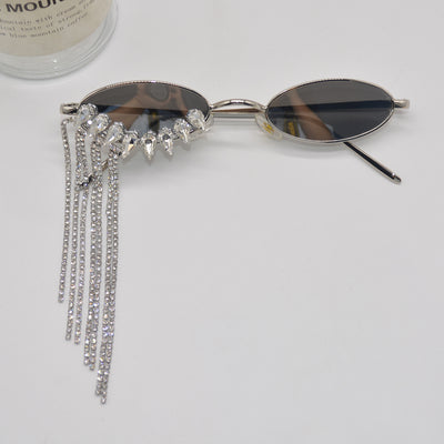 Silver oval-frame sunglasses with mirrored lenses and glamorous rhinestone tassels on one side, held by a gloved hand. - Image 4
