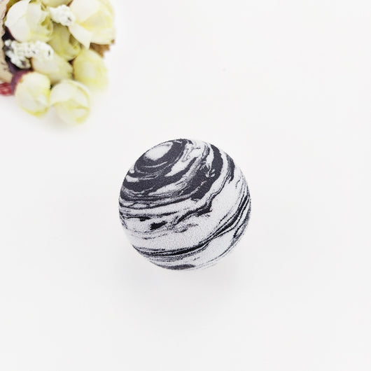 Black and white marbled EVA foam ball, a pet toy, on a white background with blurred flowers. - Image 9