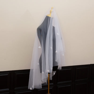 White and ivory sheer fabric swatches for a wedding veil displayed on green grass. - Image 4