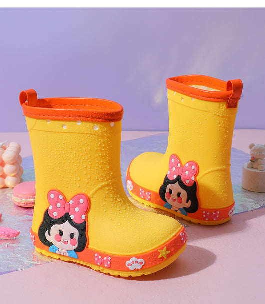 Bright yellow children's rain boots with a green cartoon dinosaur design and orange trim, held by hands. - Image 12