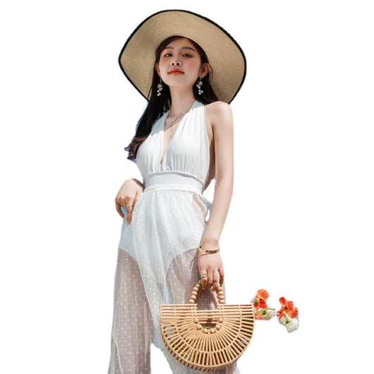 Woman in a white backless halter swimsuit with a sheer polka dot cover-up skirt, straw hat, and bamboo bag. - Image 5