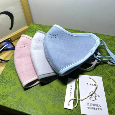 Dark gray cotton head-mounted mask with adjustable ear loops, shown in packaging on a patterned green surface. - Image 14